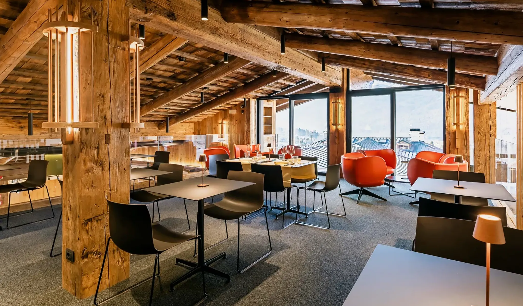 L’interno di Roof Cortina Bistrot & Lounge Bar si distingue per un’eleganza contemporanea che valorizza i materiali naturali. Le travi in legno a vista scandiscono lo spazio, mentre le grandi vetrate lasciano entrare la luce naturale e aprono la vista sui tetti e sulle montagne di Cortina. Arredi essenziali, tavoli lineari e sedute dal design moderno definiscono un ambiente accogliente e curato, pensato per momenti di relax e convivialità.